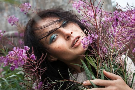 Portrait of beautiful freckled girl among the flowers.