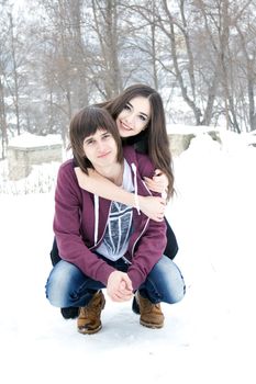 Winter, beautiful young couple piggyback in snow smiling happy and excited. 