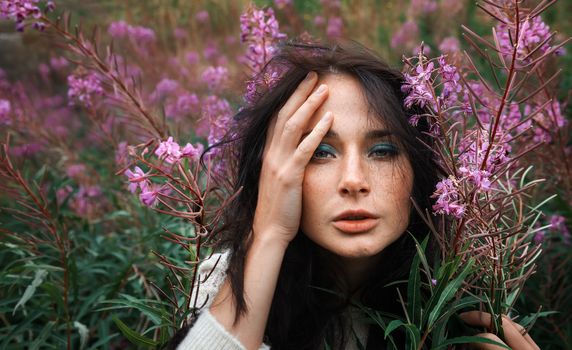 Portrait of beautiful freckled girl among the flowers.