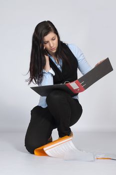 Young woman is squatting and phone and viewing documents in his hands