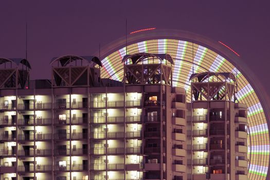 modern residential building fragment with ferris wheel traces on night sky