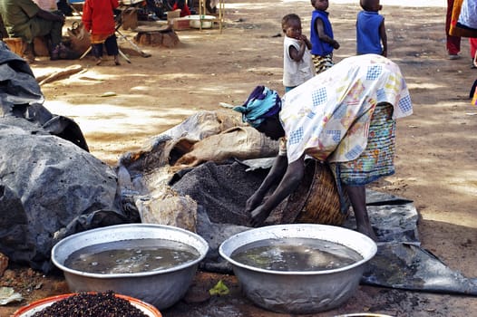 an old woman cooking local beer made from millet in Burkina Faso called Dolo in the middle of a street in Bobo-Dioulasso