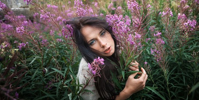 Portrait of beautiful freckled girl among the flowers.