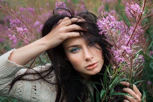 Portrait of beautiful freckled girl among the flowers.