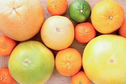 Background of assorted citrus fruit with lemon, lime, orange, tangerine, clementine and grapefruit, close up view from above on a wooden background