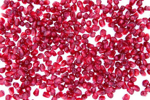 Creative background made of seeds of fresh and nutritious pomegranate, on white, close-up high-angle shot