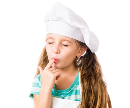 little girl in chef hat licks a finger with eyes closed on a white background