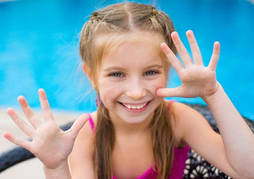 little cute girl holding hands up near a swimming pool