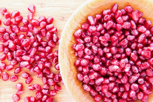 Wooden bowl filled with cleaned and prepared succulent ripe pomegranate seeds or arils rich in vItamin K and antioxidants