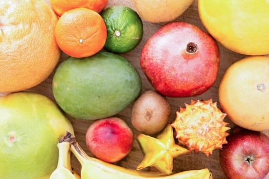 Background of assorted citrus fruit with lemon, lime, orange, tangerine, clementine and grapefruit, close up view from above on a wooden background