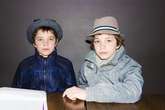 two boys wearing hats at a table in a cafe