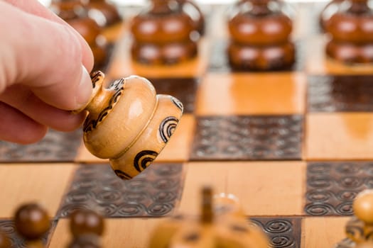 man plays chess and makes the move with chess pawn in focus