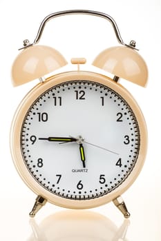 classic alarm clock on white table with reflection
