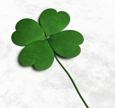 a green four-leaf clover is lying on a white and grey abstract ground