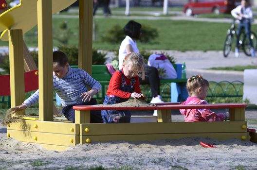 Unknown children playing in the sandbox in the Park a spring Sunny day