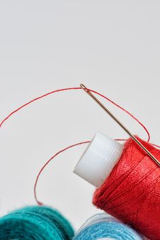 Coils of color threads and steel needle with a red thread