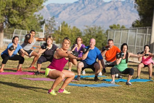Serious boot camp exercise class squatting with weights