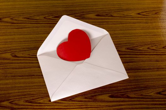 red heart with pink envelope on wooden background