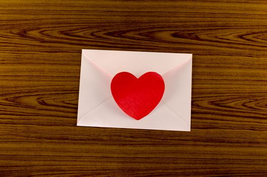 red heart with pink envelope on wooden background