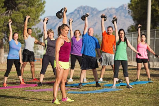 Mixed group of men and women lifting weights outdoors