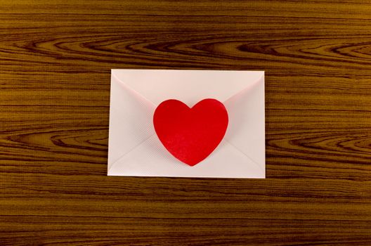 red heart with pink envelope on wooden background