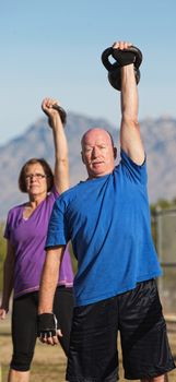 Fit pair of middle aged people exercising with weights