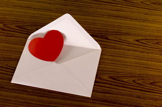 red heart with pink envelope on wooden background