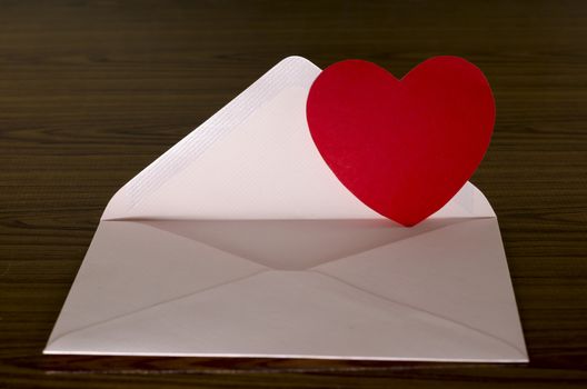 red heart with pink envelope on wooden background