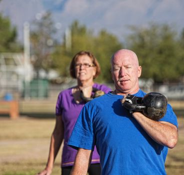 Athletic middle aged man lifting kettle bell weight