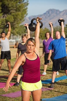 Athletic woman teaching boot camp fitness class outdoors