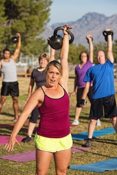 Fit female leading strength training class outdoors