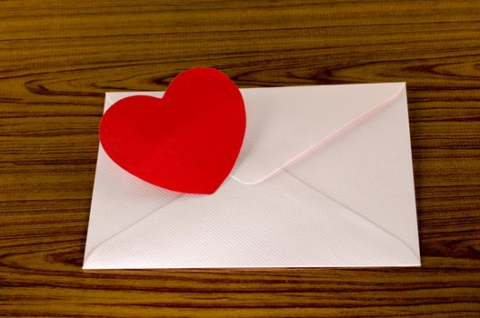 red heart with pink envelope on wooden background