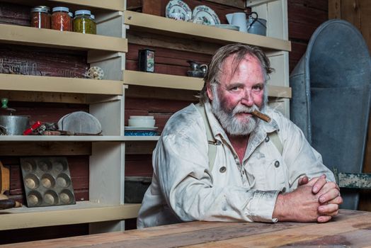 Smoking Western Man Looks Towards You as he Sits at Table