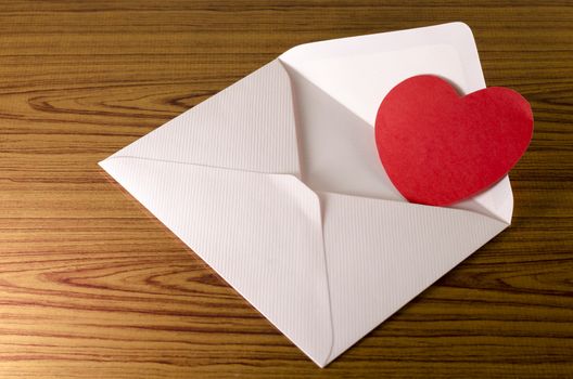 red heart with pink envelope on wooden background