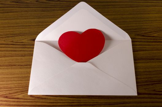 red heart with pink envelope on wooden background
