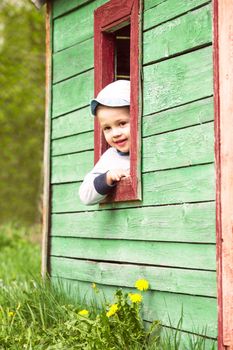 Boy plays in little 
toy wooden house outdoor