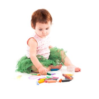 Toddler girl draws with 
wax crayons on the paper