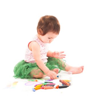 Toddler girl draws with 
wax crayons on the paper