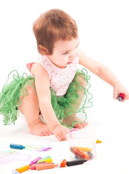 Toddler girl draws with 
wax crayons on the paper