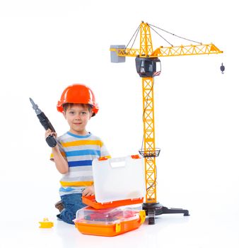 Little builder. Boy in a helmet plays in the builder with tools. Isolated over white.