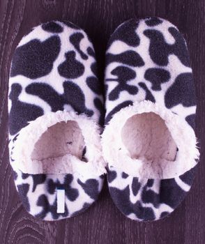 Black and white leopard slippers over wooden table