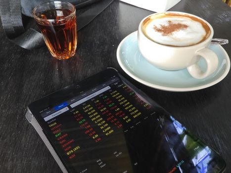 cup of coffee and Display stock market on tablet 