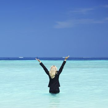 Happy business woman standing in sea waves