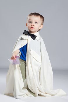 Boy toddler businessman, standing dressed in grown-shirt with bow tie, hand holding euro