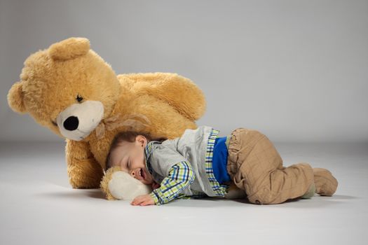 Boy toddler lying and snuggle to a large teddy bear