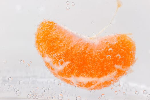 Orange (mandarin) falling in water with air bubbles