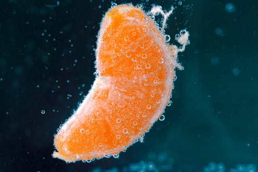 Orange (mandarin) falling in water with air bubbles