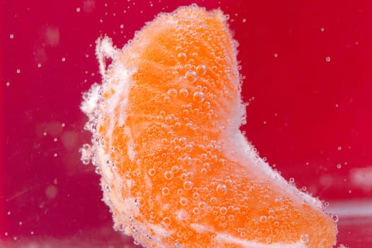 Orange (mandarin) falling in water with air bubbles