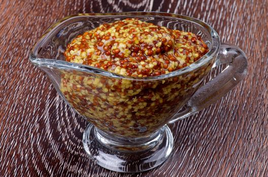 Gourmet Whole Grain Mustard in Glass Gravy Boat isolated on Wooden background