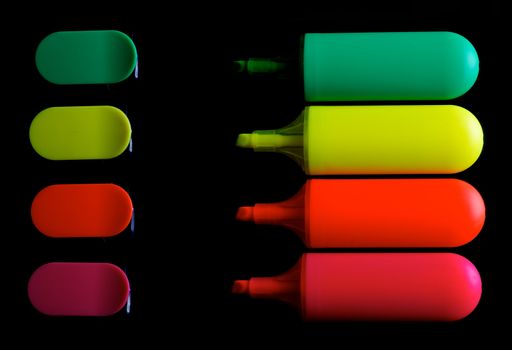 Red, Orange, Yellow and Green Fluorescent Highlighter Pens with Caps In a Row isolated on black background